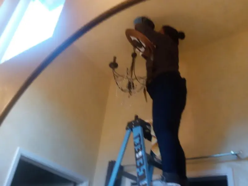 Electrician installing a chandelier in a Grenada residence